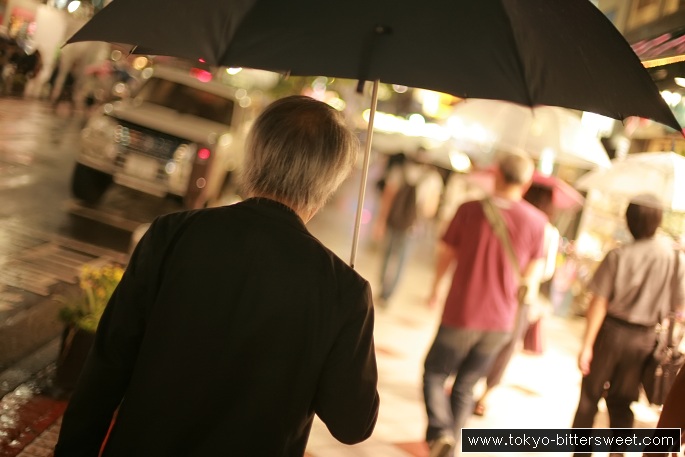 Japanese salaryman with umbrella on the sidewalk.