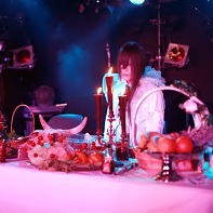 A lonely actor of MONT★SUCHT sitting at a food-laden table.