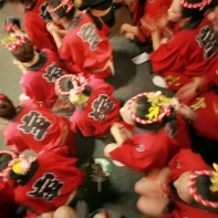 A group of female dancers rests while the men perform a special dance.