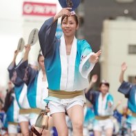 A group of young women dancers wearing the traditional men's costume waving fans.