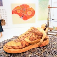 A weird sculpture of a man resting in a shoe.