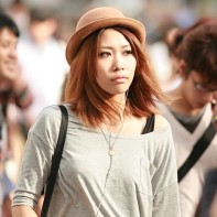 Young Japanese woman with light-brown hair and hat in the Shibuya afternoon sun.