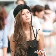 A stylish Japanese girl with black fur hat holding her mobile.