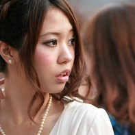 A young Japanese lady with pearl jewelry looking to her left.