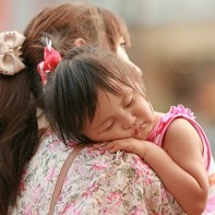A Japanese toddler being carried by her mother at Shibuya crossing.