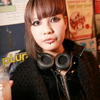 Japanese goth girl with headphones holding a drink.