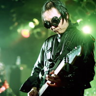 Psydoll's guitar player Ucchi with singer Nekoi in the background.