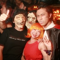 A group of Japanese Helloween fans in scary costumes accompanied by a lady in red.