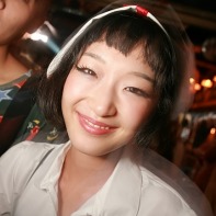 Japanese girl in a white nurse Halloween outfit smiling.
