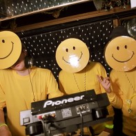 A team of three smiley DJs at the turntables of the Trump Room.