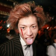Japanese guy suited up and sticking out his tongue.