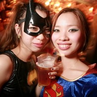 Japanese girls dressed up in Batgirl and Supergirl costumes.