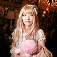 Blonde Japanese girl with a cute lolita outfit and a pink stuffed toy.