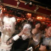 People in cool and crazy costumes in front of the DJ booth.